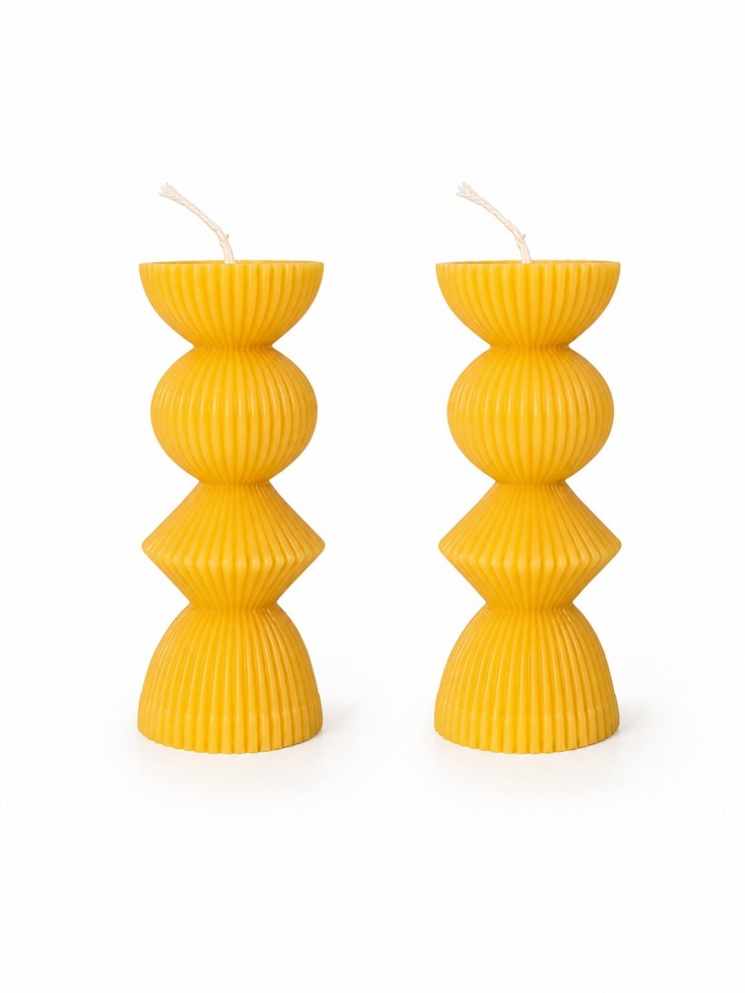 Two bright yellow ribbed pillar candles with a stacked geometric design, shown on a clean white background.