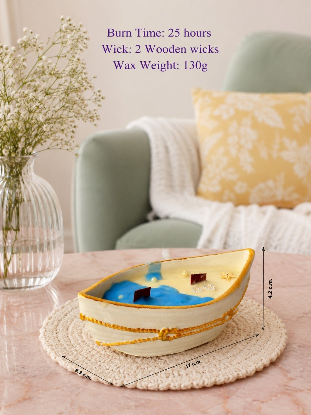 A decorative boat-shaped candle jar with 2 wooden wicks and with a cream-colored exterior, gold trim, and a blue and yellow coconut wax with 2 wooden wicks shown on a woven placemat in a softly styled living room setting. Purple text at the top lists burn time, wick count, and wax weight, with dimension lines indicating the boat's size.